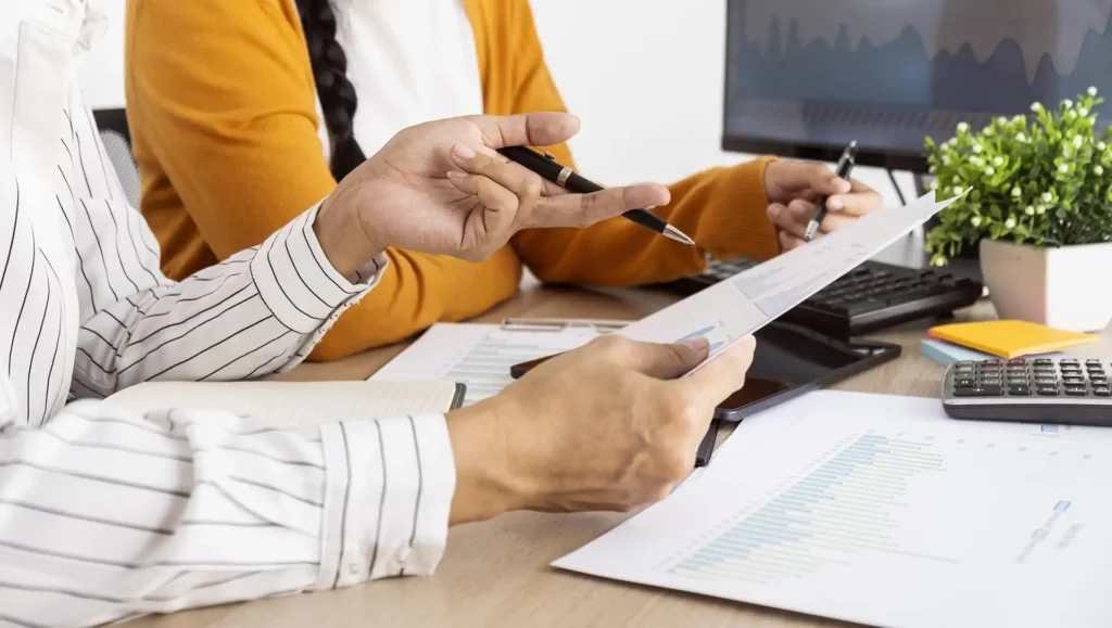 Two people reviewing a tender document and prequalification checklist